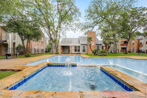 a swimming pool with a fountain in front of an apartment building