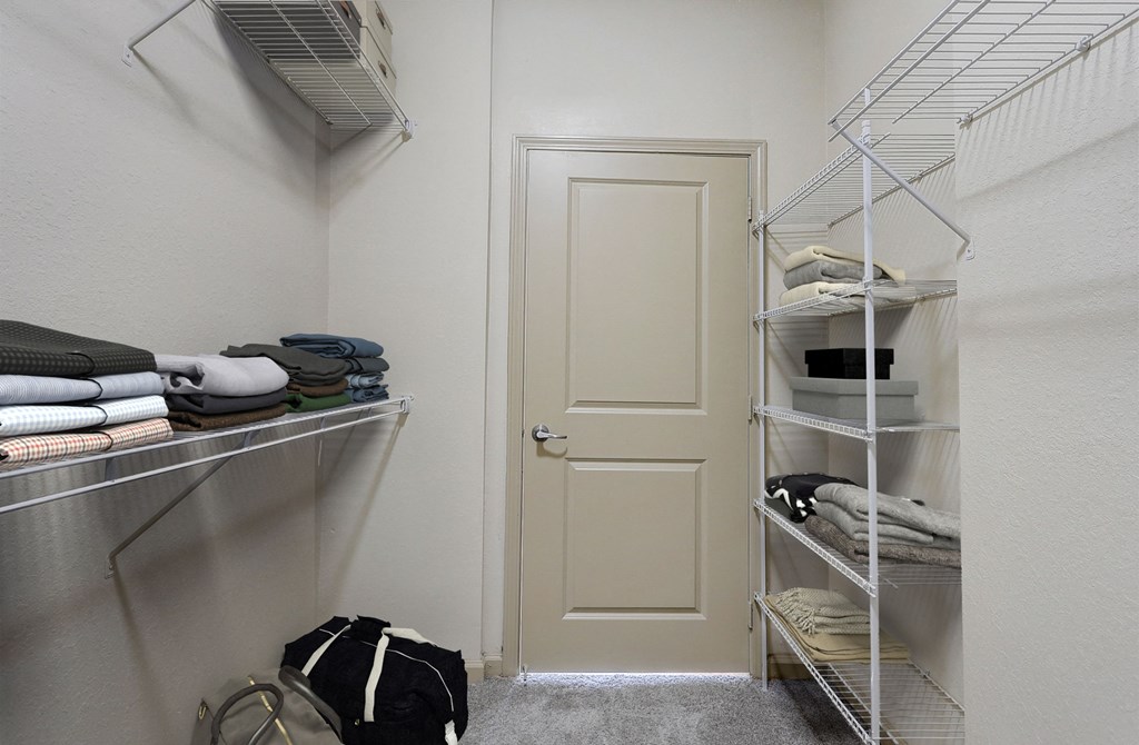a walk in closet with shelves and a closet door