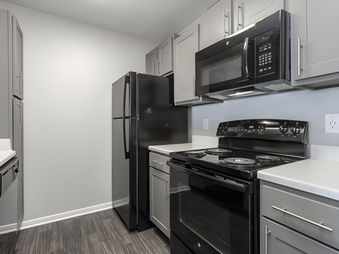 A black refrigerator and stove in a kitchen with white cabinets.