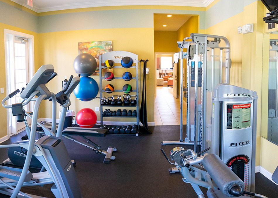 A gym with a variety of equipment including a treadmill, weights, and a fitness ball.