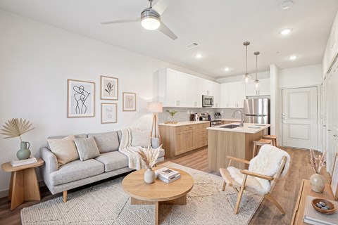 A living room with a grey couch, a wooden coffee table, and a kitchen in the background.