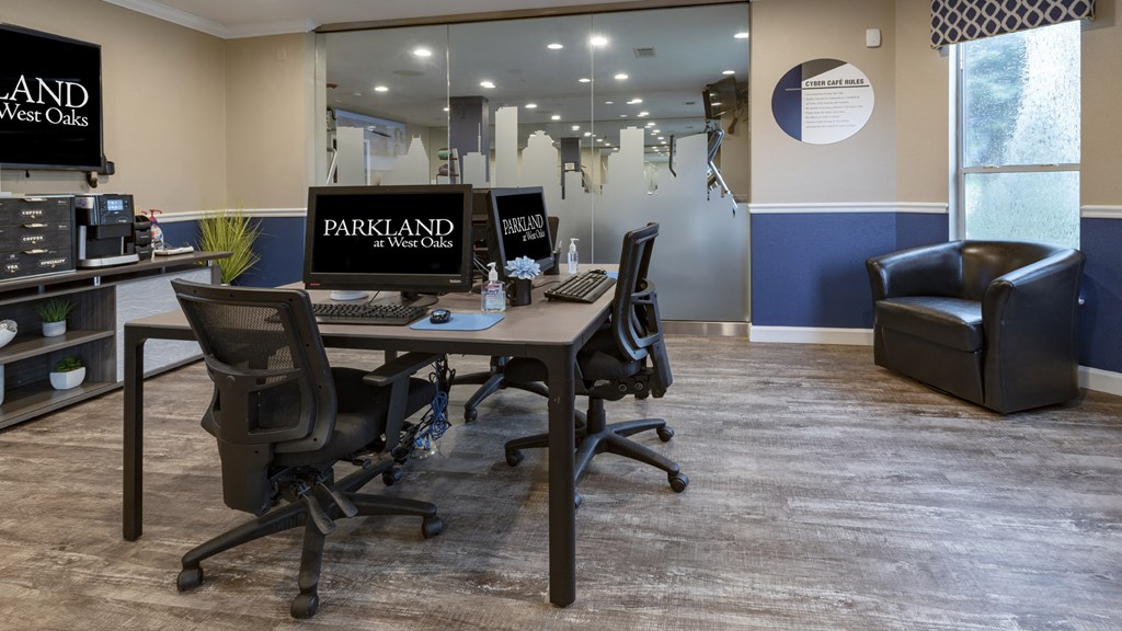 a desk with two computer monitors and a chair in an office