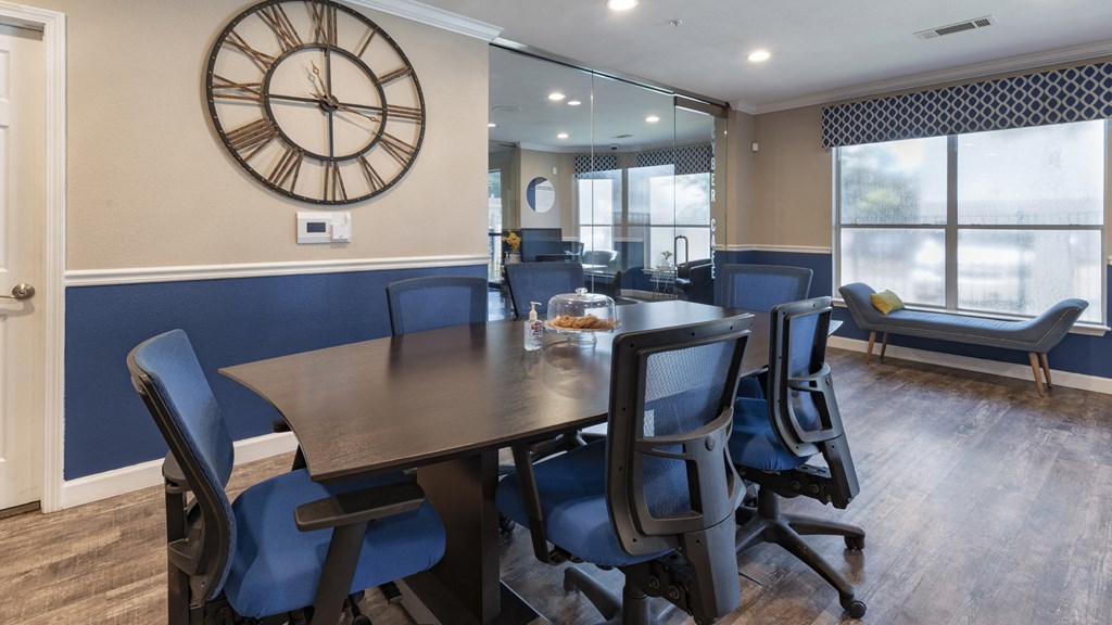 a conference room with a table and chairs and a clock on the wall