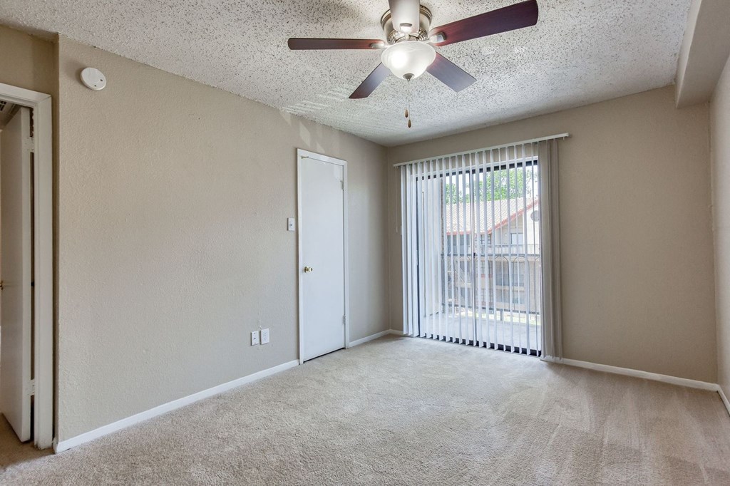 an empty living room with a ceiling fan and a window