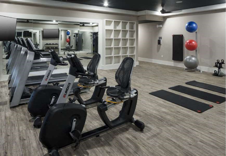 a gym with a row of exercise bikes and a large mirror