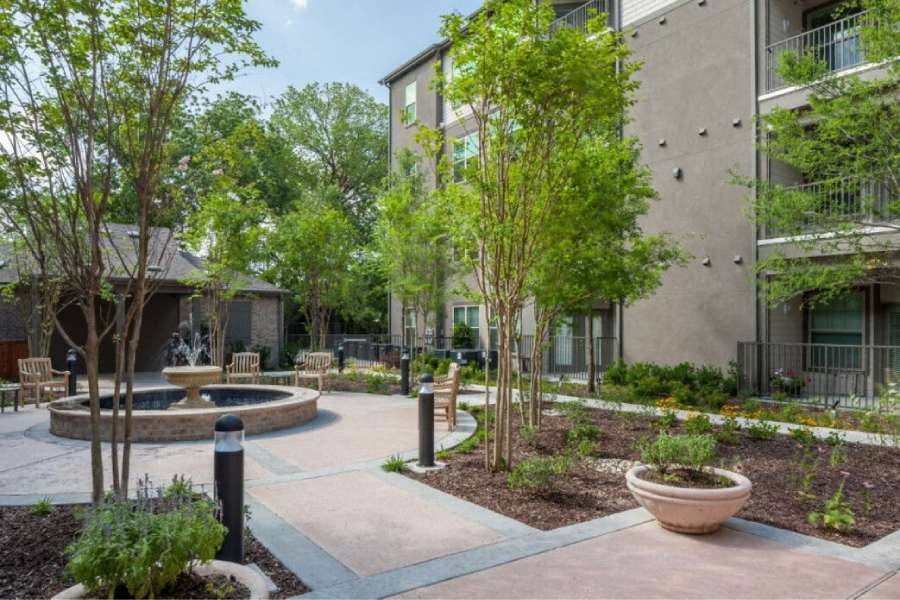 a courtyard with a fountain and trees in front of an apartment building