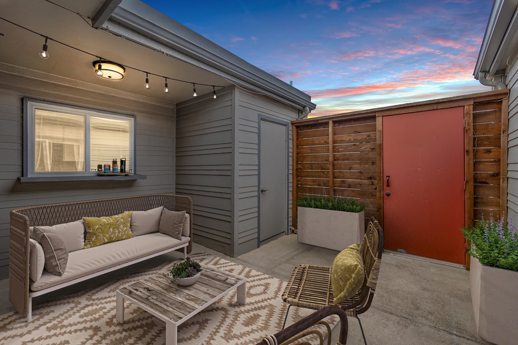 a patio with a couch and chairs and a red door