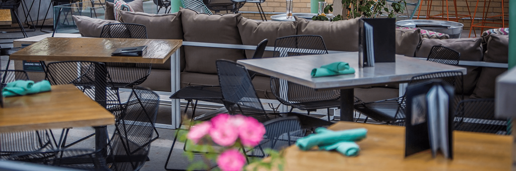 a restaurant with tables and chairs and flowers in the foreground