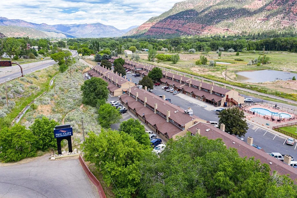 an aerial view of a building with a parking lot and mountains in the background