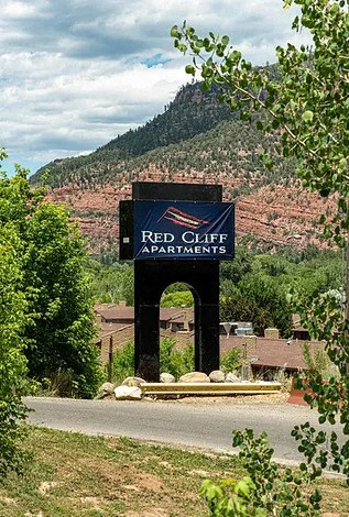 a sign that says red cliff apartments with a mountain in the background