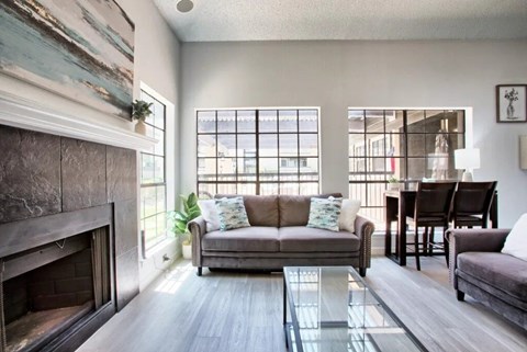 A living room with a grey couch and a fireplace.