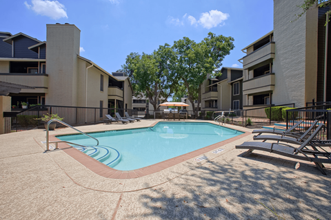 A swimming pool surrounded by apartment buildings on a sunny day.