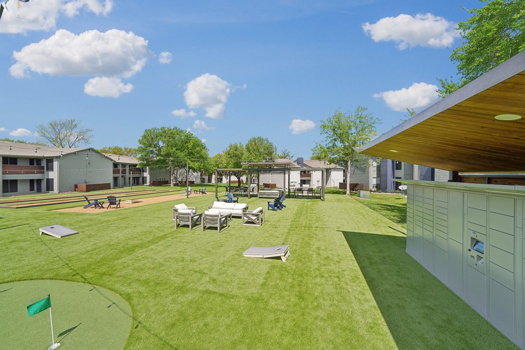 a backyard with tables and chairs on a grass field