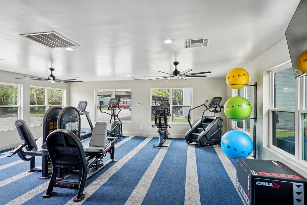 a gym with treadmills and other exercise equipment in a room with windows