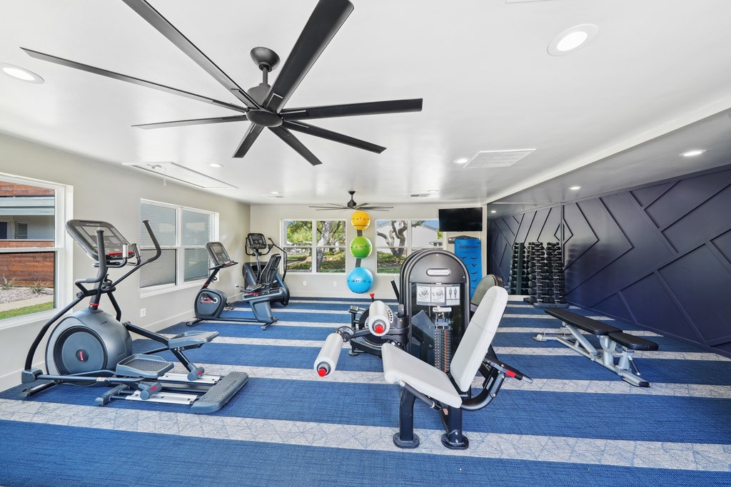 a home gym with exercise equipment and a ceiling fan