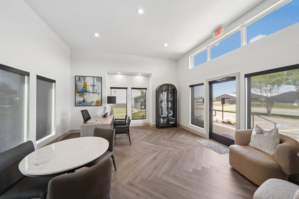 a living room with couches and a round table and windows