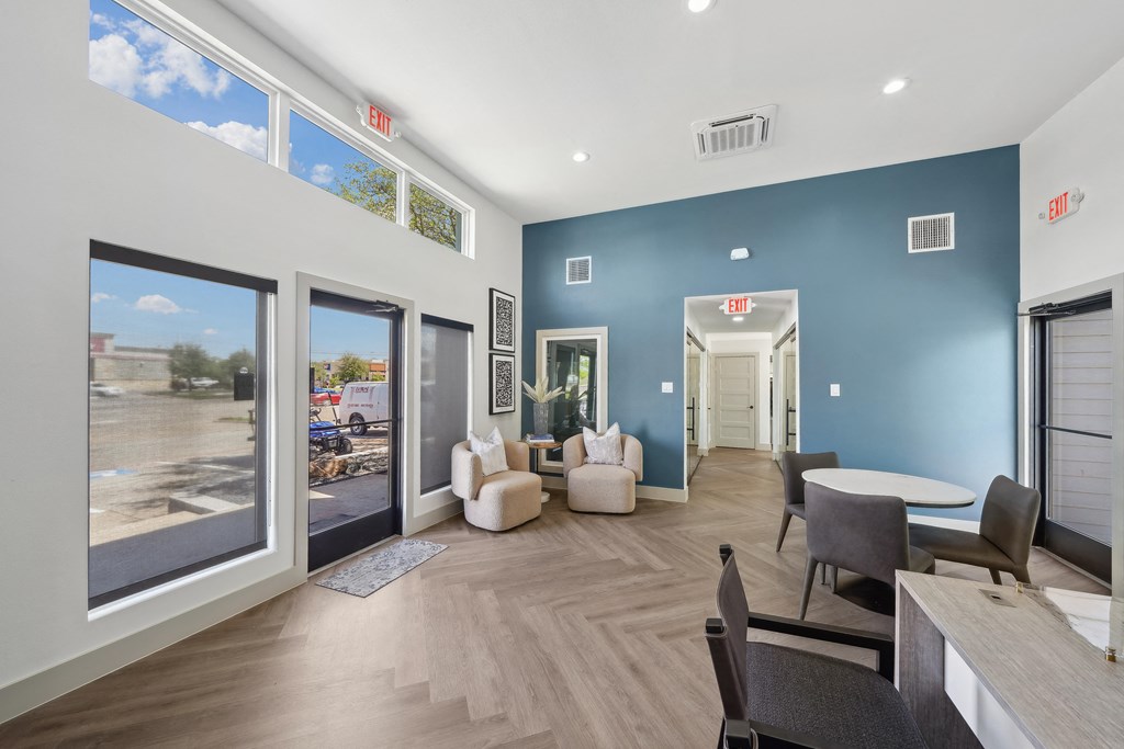 a living room with blue walls and a large window and a table and chairs