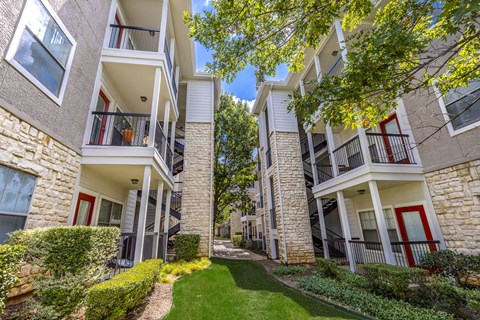 A sunny day at apartment buildings with green lawns and trees.
