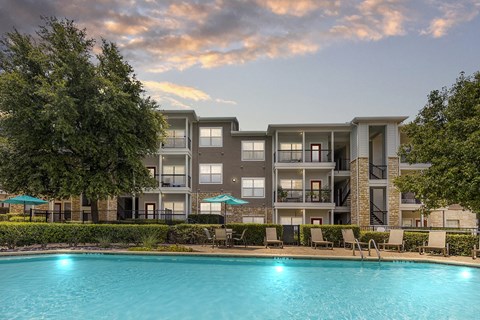A large apartment complex with a pool in the foreground.
