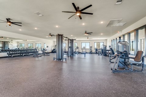 A spacious gym with a variety of equipment and a ceiling fan.
