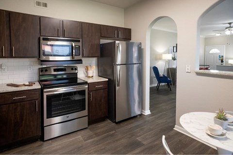 A kitchen with a refrigerator, oven, and microwave.