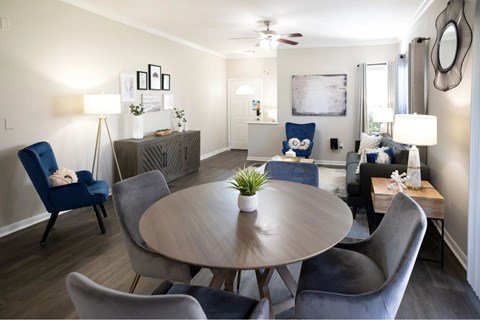A living room with a round table and blue chairs.