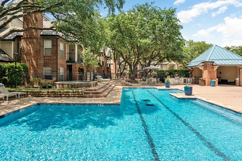 Large Dallas, TX pool deck with lap lanes, shaded pavilion, and surrounding trees.