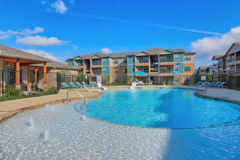A large outdoor swimming pool with a fountain in the middle.
