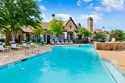 Resort-style swimming pool with expansive deck seating and clubhouse views in Lewisville, TX.