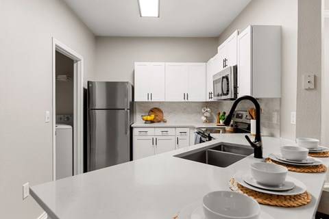 A modern kitchen with white cabinets and stainless steel appliances.