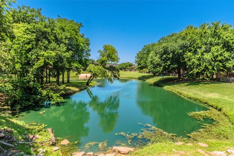 A serene landscape with a river flowing through a lush green park.