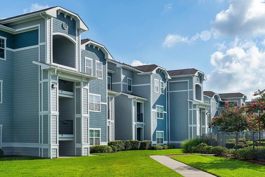 a row of blue apartment buildings with a sidewalk