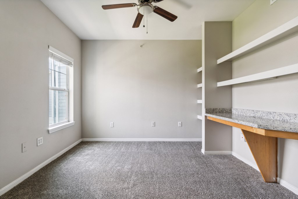 an empty room with a desk and a ceiling fan