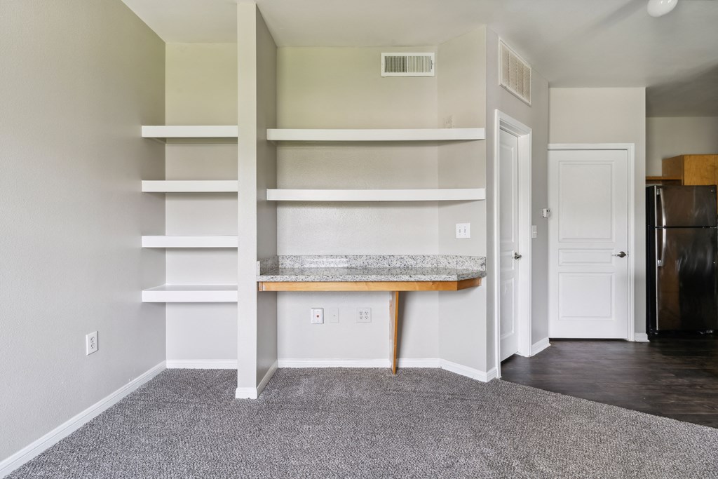 an empty room with white shelves and a counter and a door