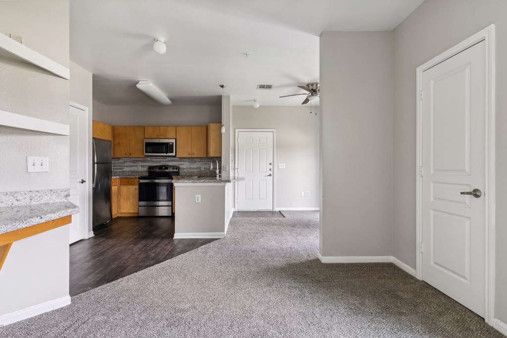 an empty kitchen and living room with a ceiling fan
