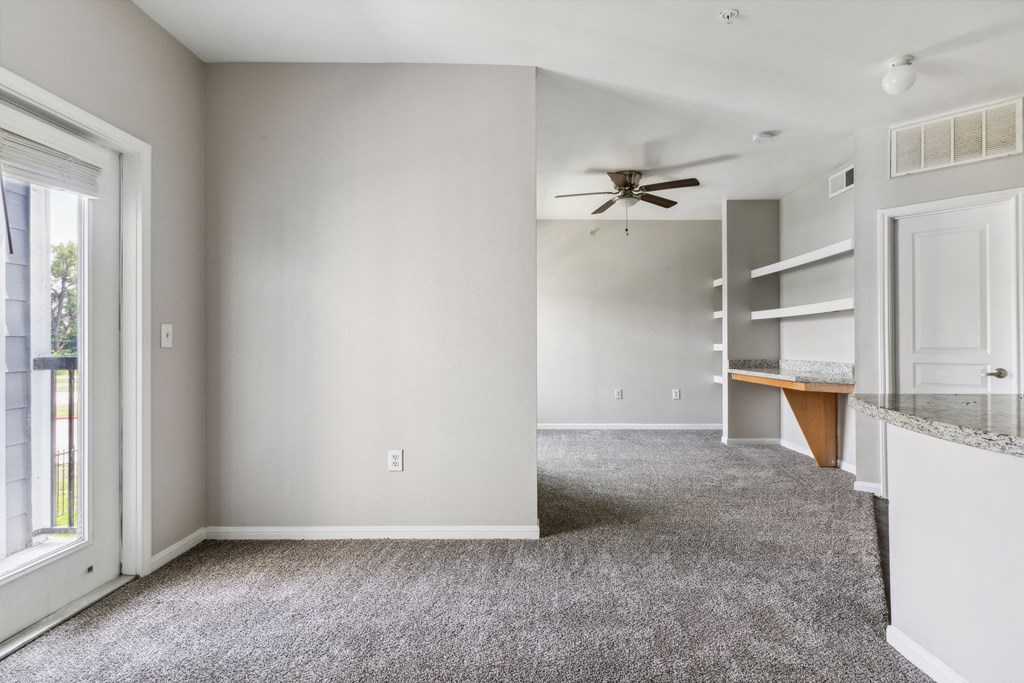 an empty living room with carpet and a ceiling fan