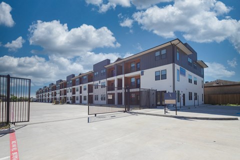 Gated apartment community entrance with modern townhomes at The Aurea Apartments, Houston