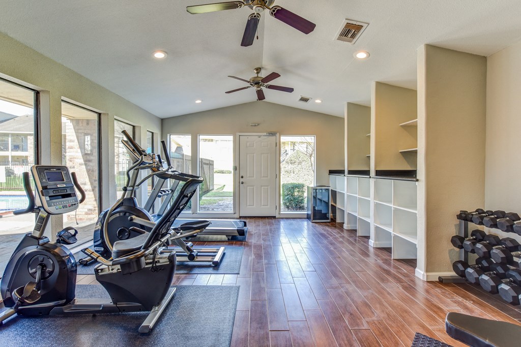 a home gym with exercise machines and a ceiling fan