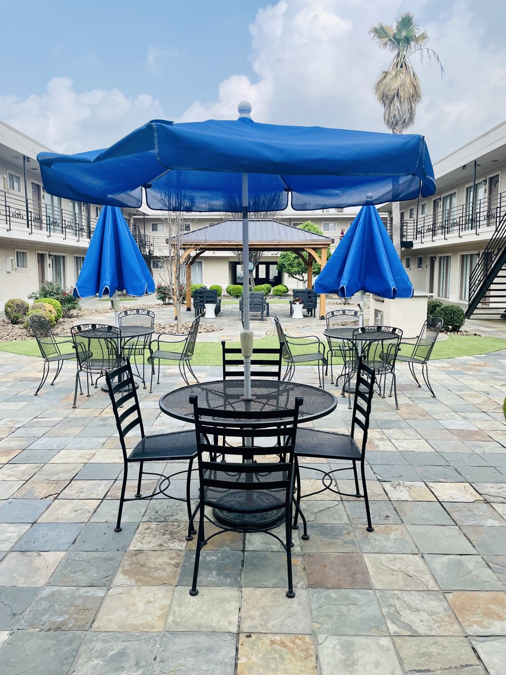 a patio with tables and umbrellas in a hotel courtyard