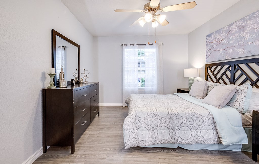 A bedroom with a large bed and a dresser with a mirror above it.