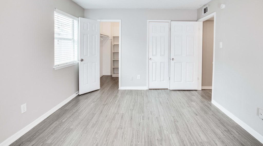 A room with white doors and wooden flooring.