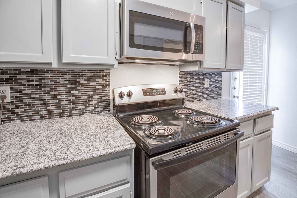 A modern kitchen with a stove top oven and microwave above it.