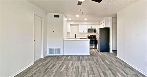 A spacious kitchen with a bar counter and a ceiling fan.
