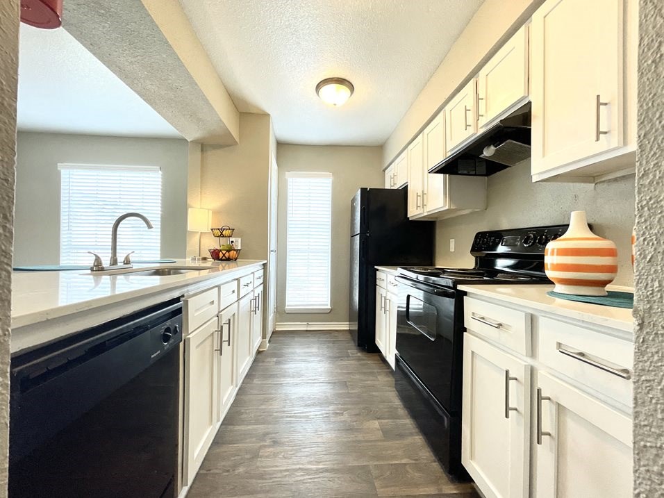 a kitchen with white cabinets and black appliances  at The Alara, Houston, TX, 77060