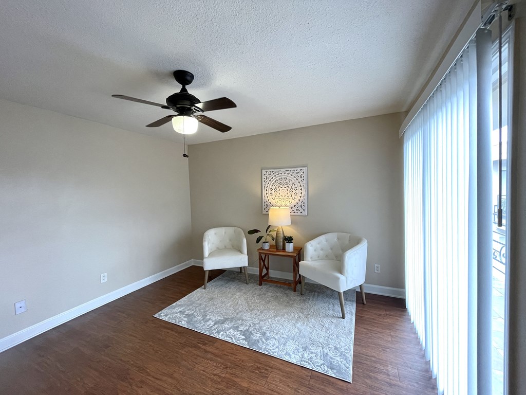 A room with a ceiling fan and two chairs.