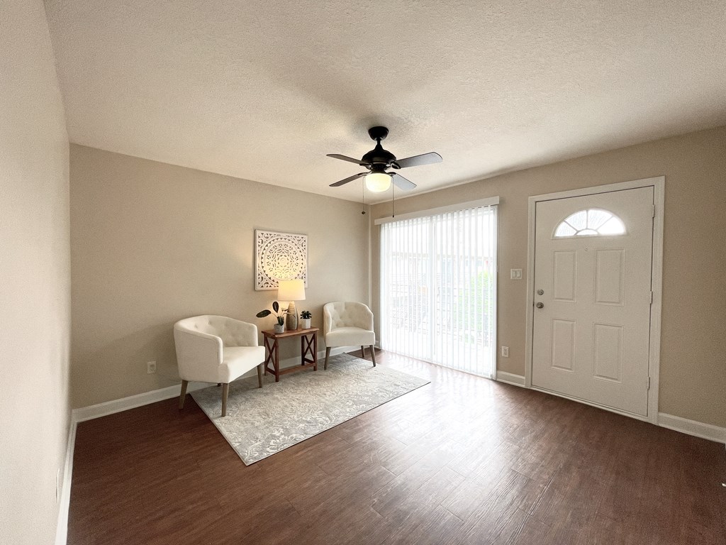 an empty living room with a ceiling fan and a door to a balcony
