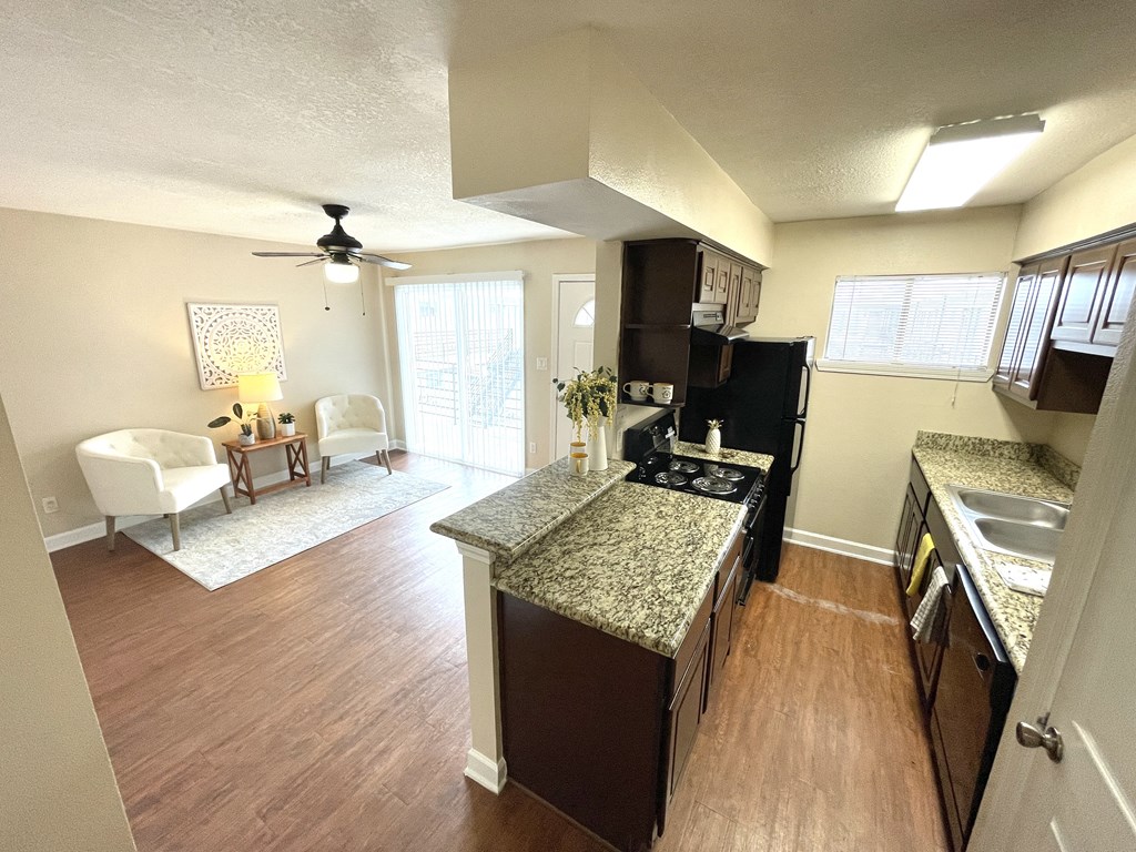 A kitchen with a black refrigerator and brown cabinets.