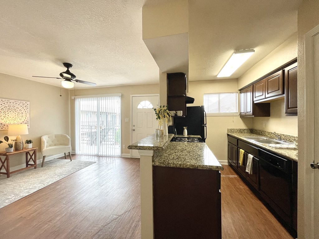 A kitchen with dark wood cabinets and a marble countertop.