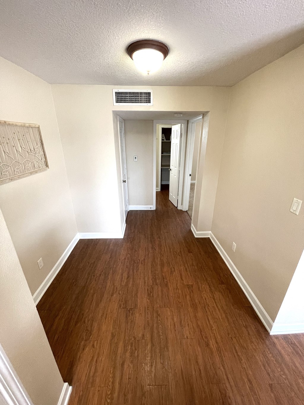 A long hallway with wood floors and white walls.
