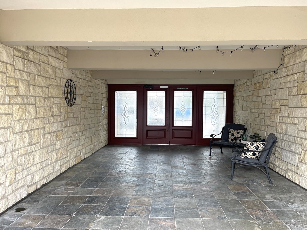 a view of the front porch of a house with red doors and a stone wall